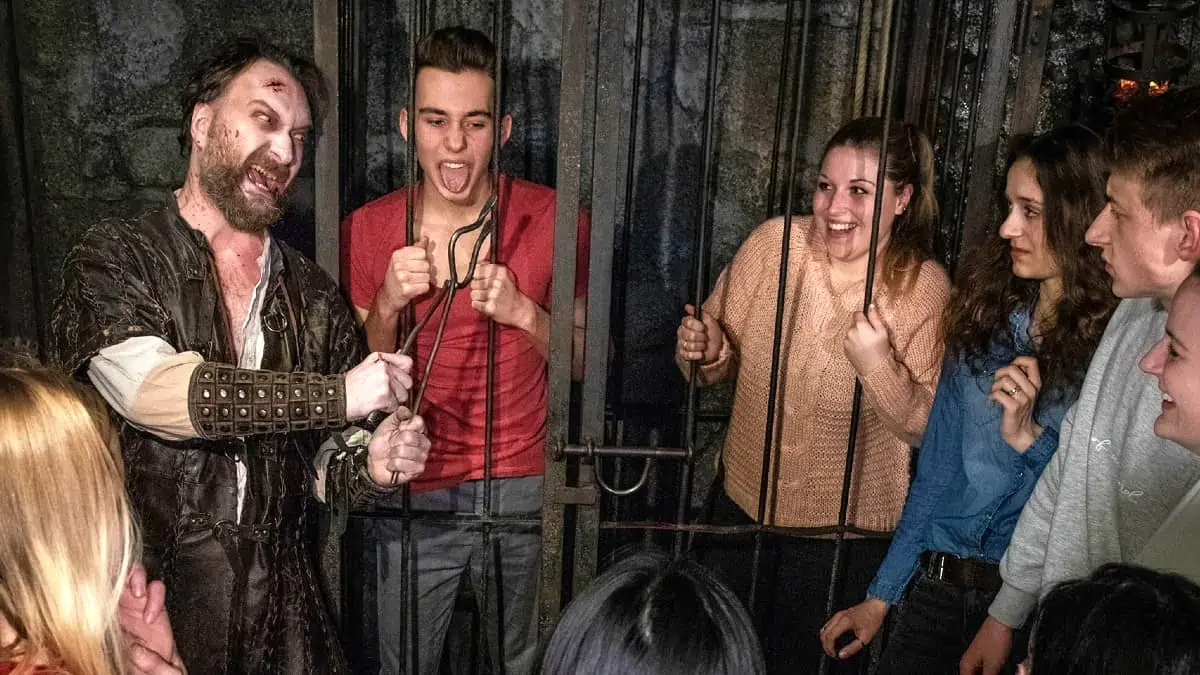Berlin-Dungeon Actor dressed as a medieval torturer interacts with laughing visitors during a performance at the Berlin Dungeon