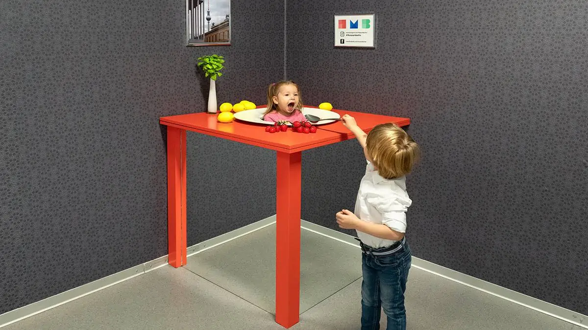 Kids-enjoying-Illuseum-in-Berlin Two children playing with a head-on-a-platter illusion at Illuseum Berlin