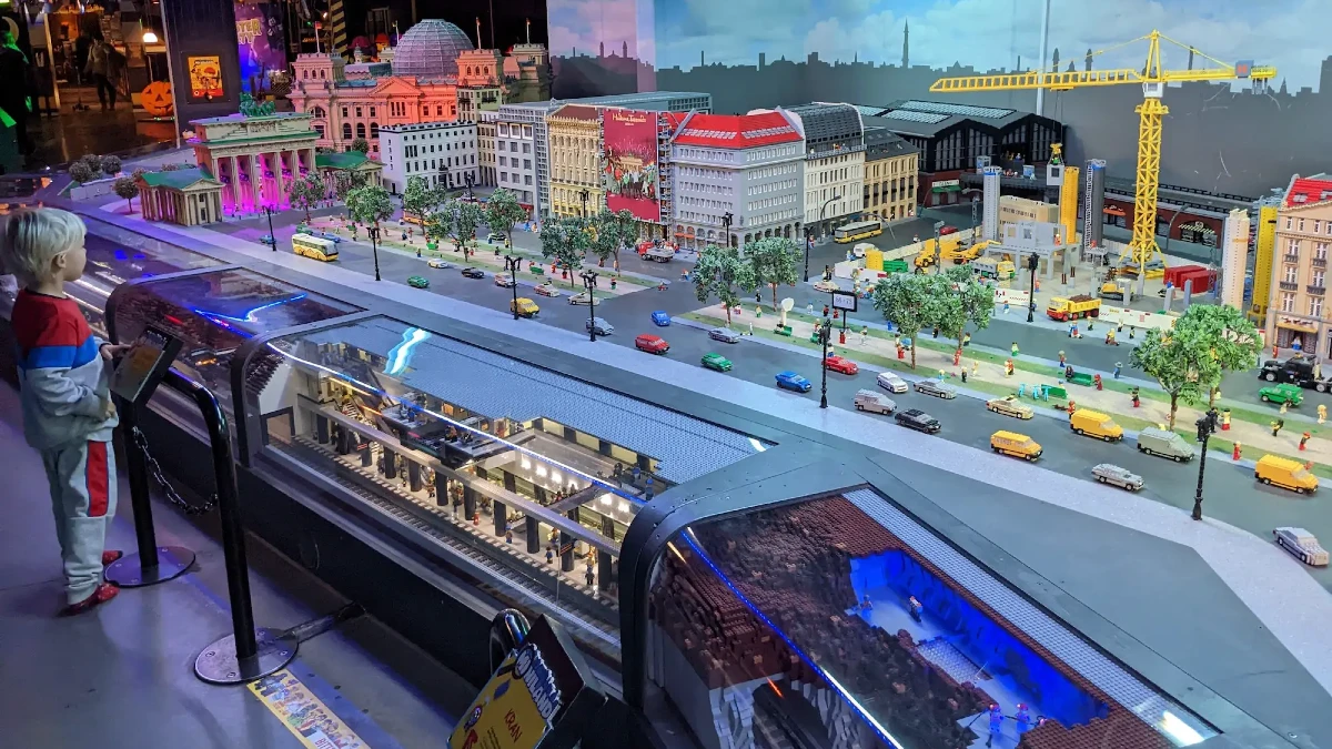 Legoland-Discovery-Centre-Berlin Child watching an intricate LEGO model of Berlin’s cityscape with buildings, streets, cars, and an underground train at Legoland Discovery Centre Berlin.