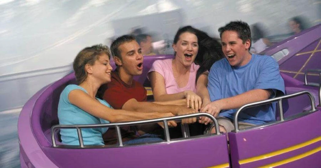 A group of four friends enjoy a spinning amusement park ride