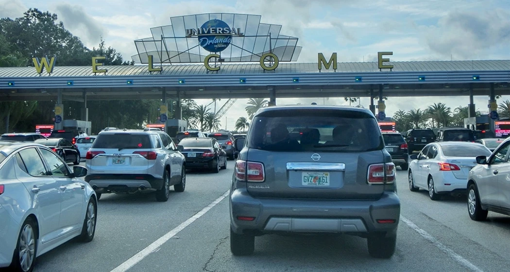 Cars line up at Universal Orlando Resort's entrance under a "Welcome" sign
